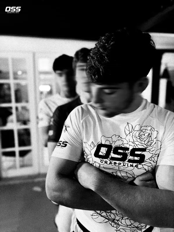 Grappler de brazos cruzados con la polera blanca OSS