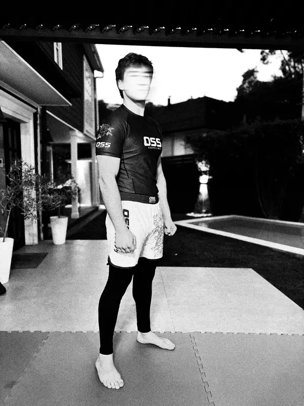 Grappler con polera negra y short blanco junto a la piscina